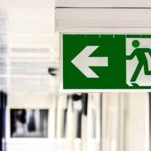 Green emergency exit sign with directional arrow in a hallway.